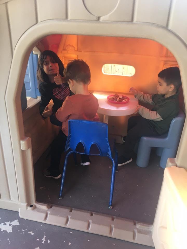 Three children playing in a small playhouse