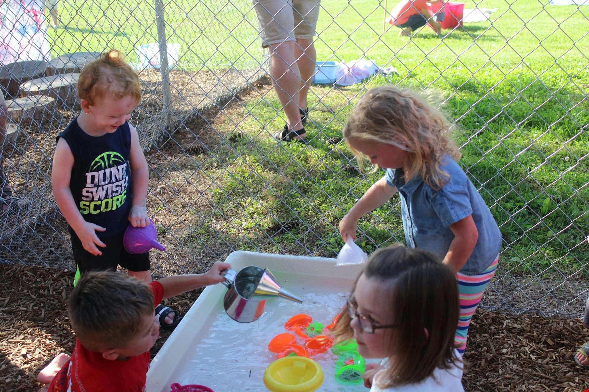 Children playing with water table and toys outdoors