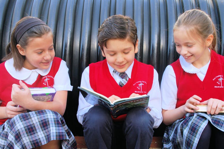 Three children in uniform reading books