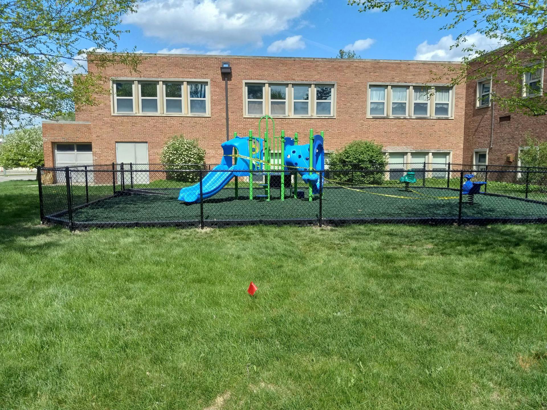 Playground with blue and green equipment in front of a brick building