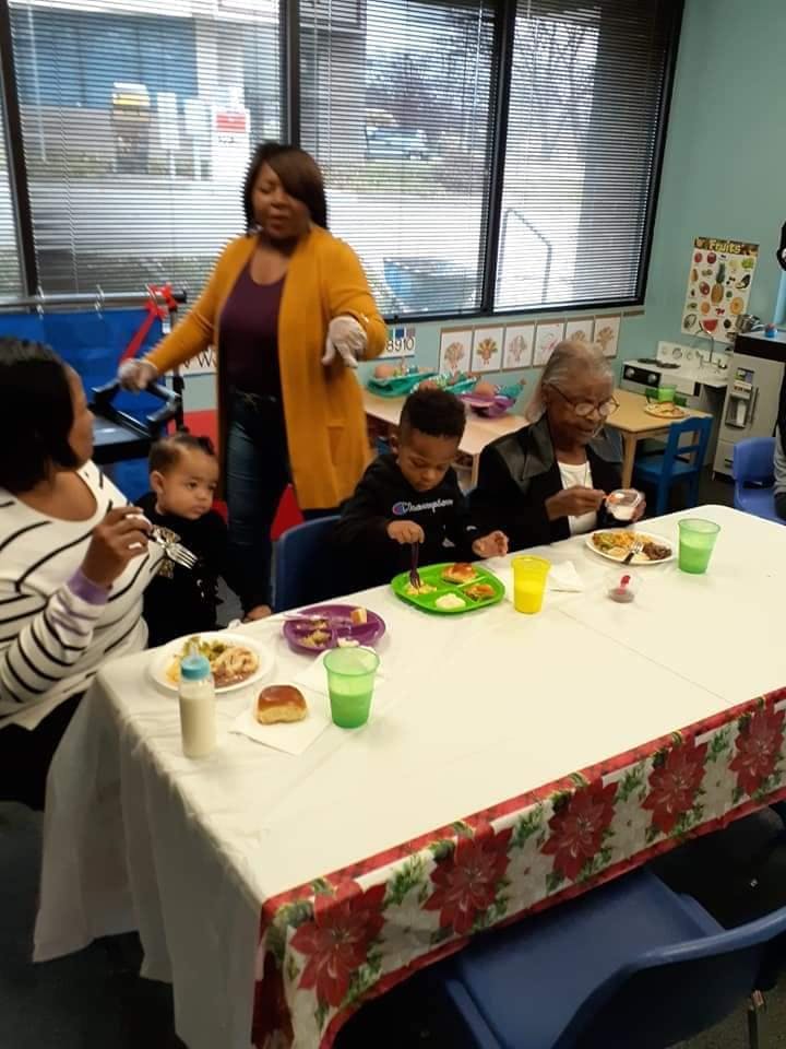People and children eating at a table in a classroom