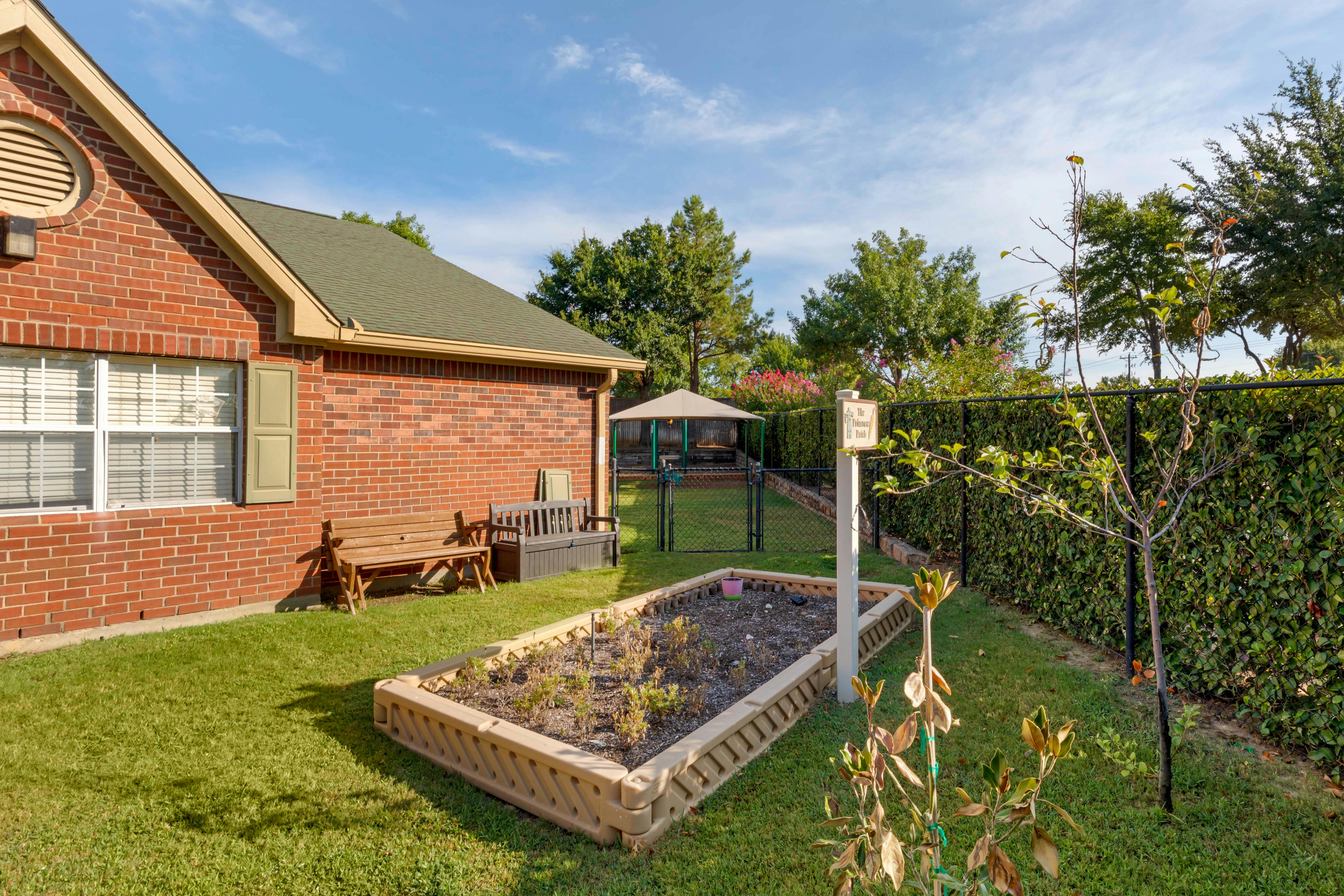 Brick building exterior with benches and garden beds on a sunny day