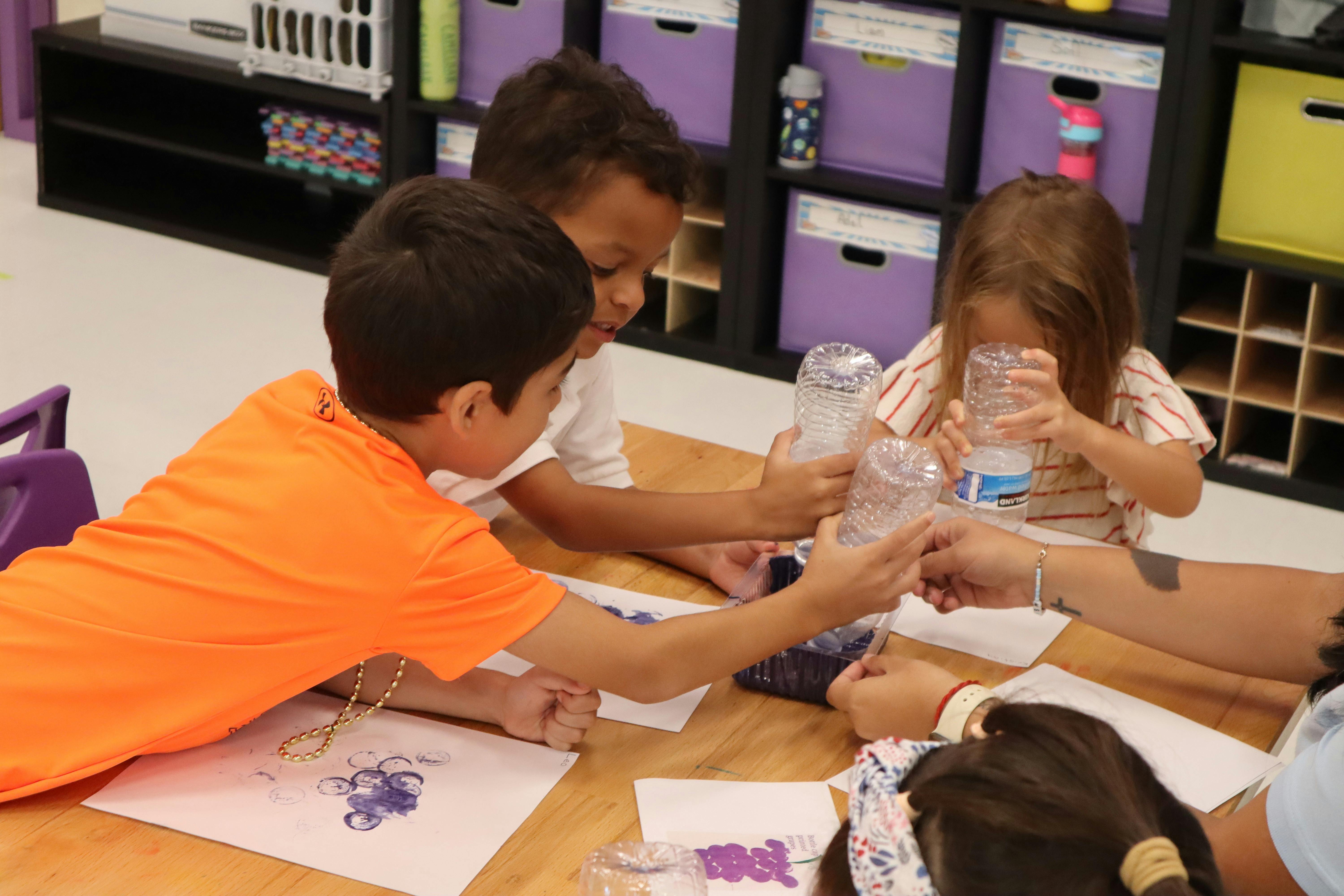 Children at a table with plastic bottles and paper cups