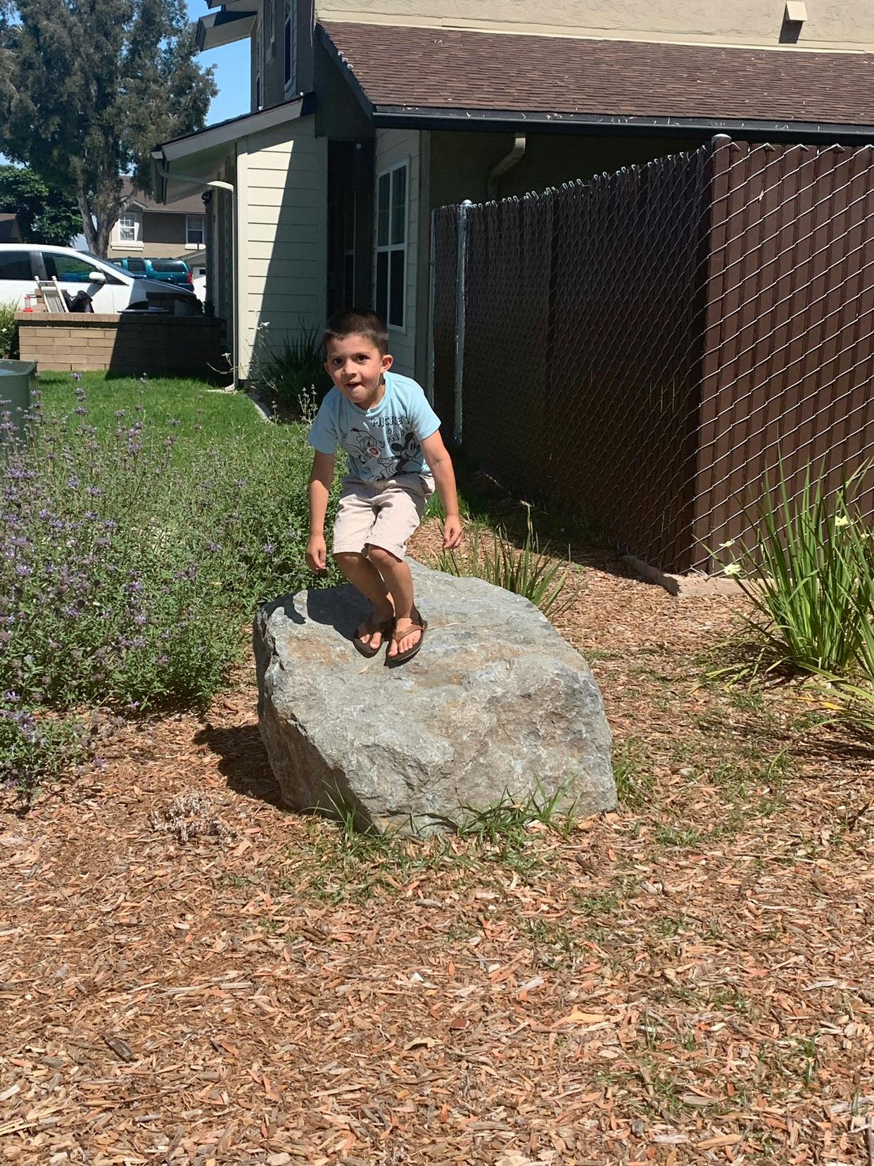 Child jumping on a large rock outdoors