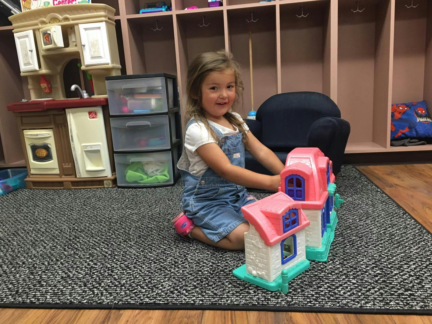 Child playing with a toy house on a rug