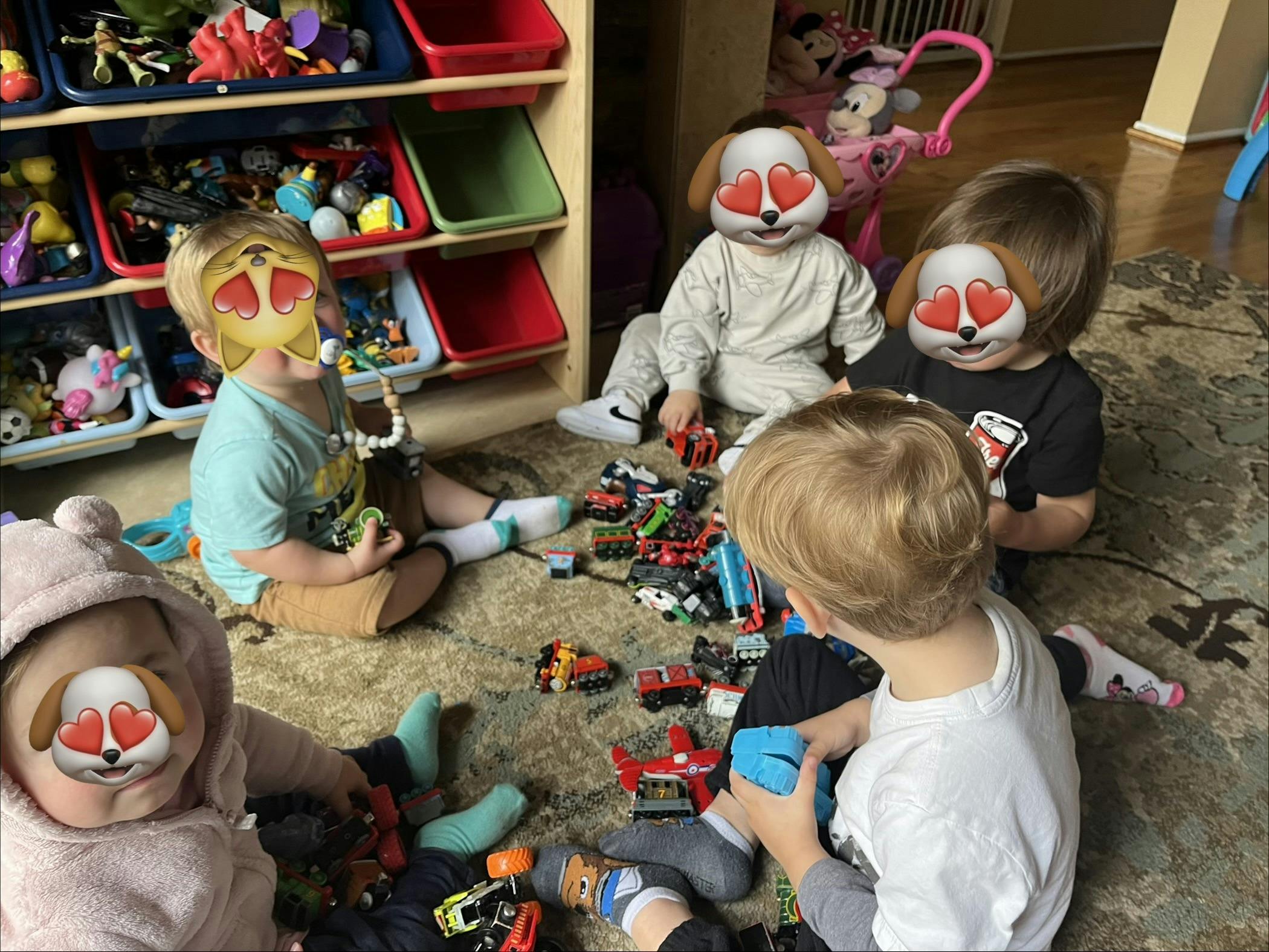 Children sitting on a rug playing with toy cars and trains