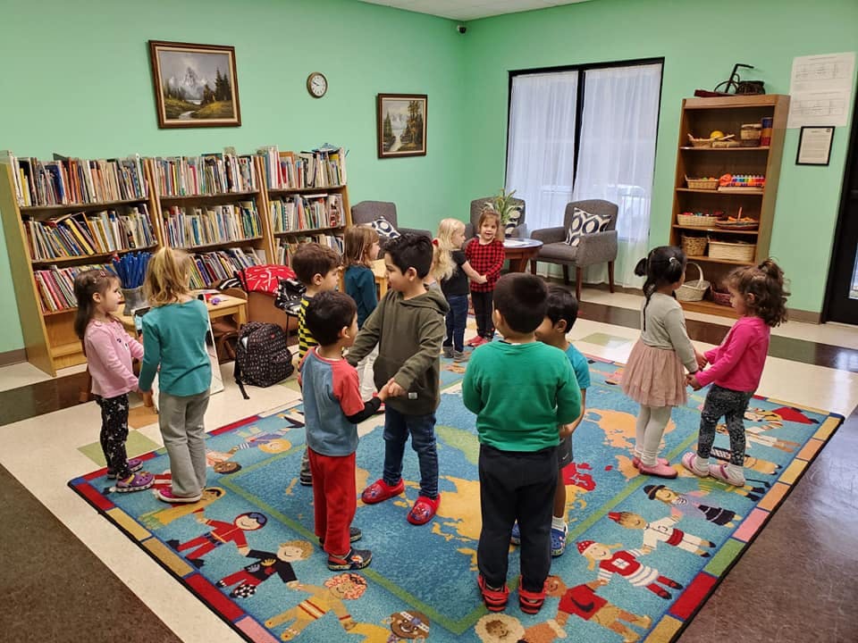 Children holding hands in a circle in a classroom