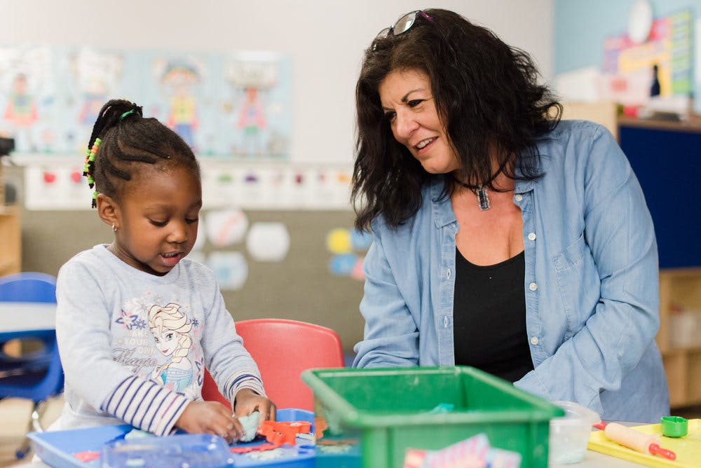 Adult and child playing with toys in a classroom