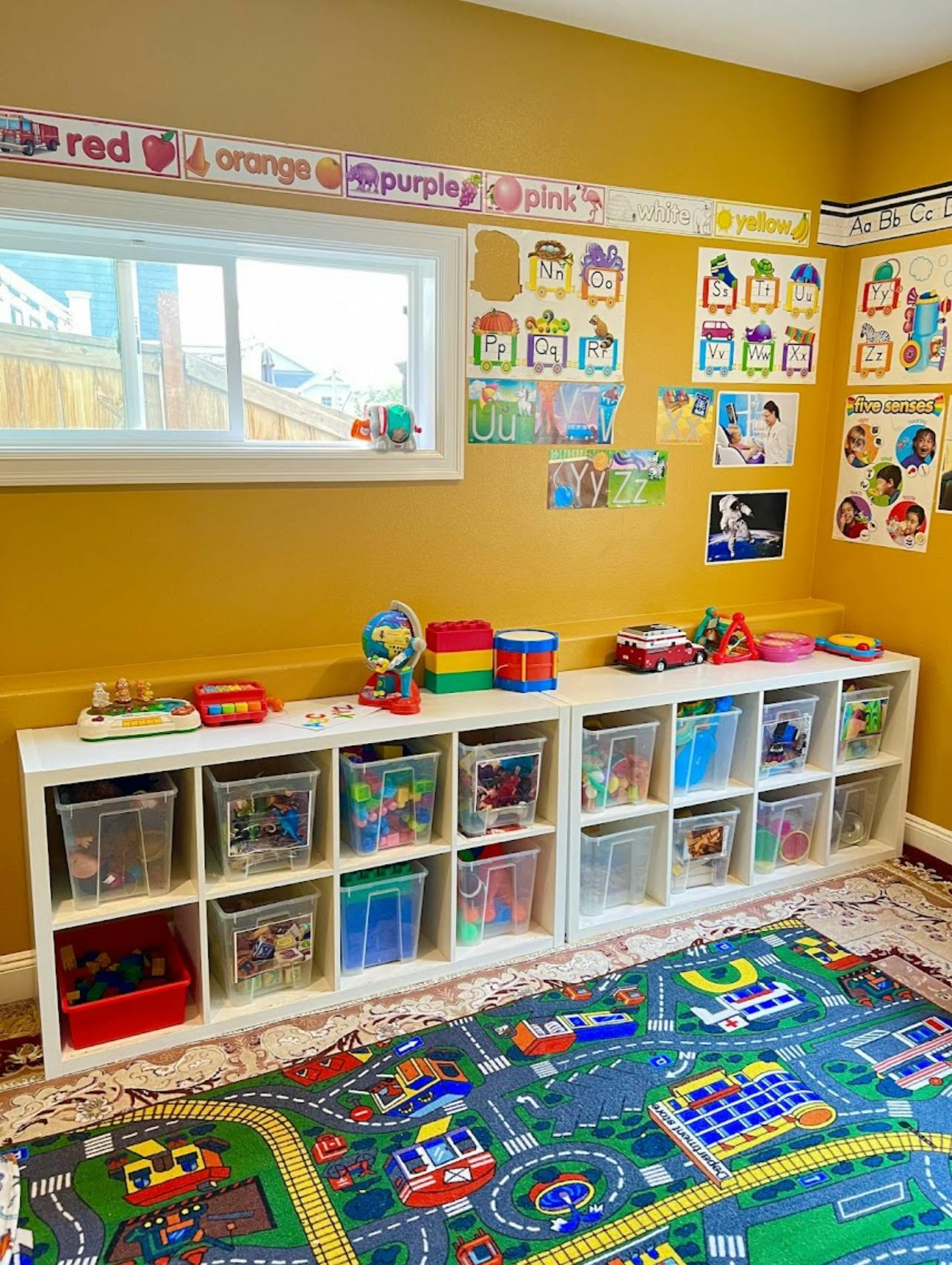 Playroom with toy storage shelves, colorful rug, and window