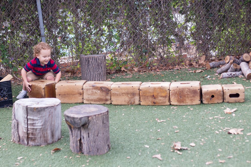 Child playing with wooden blocks outdoors