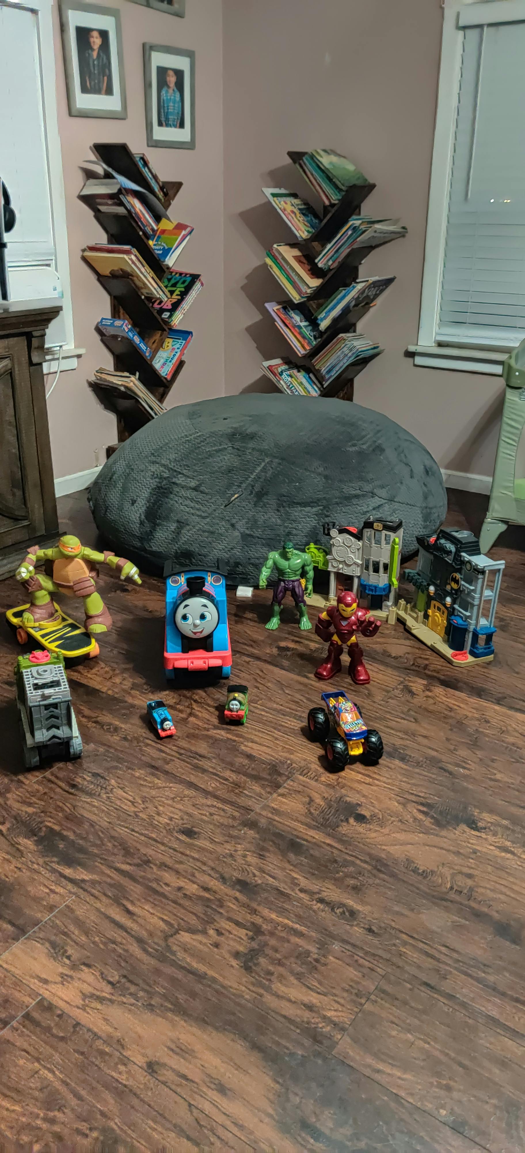 Assortment of toys on a wooden floor with bookshelves in the background