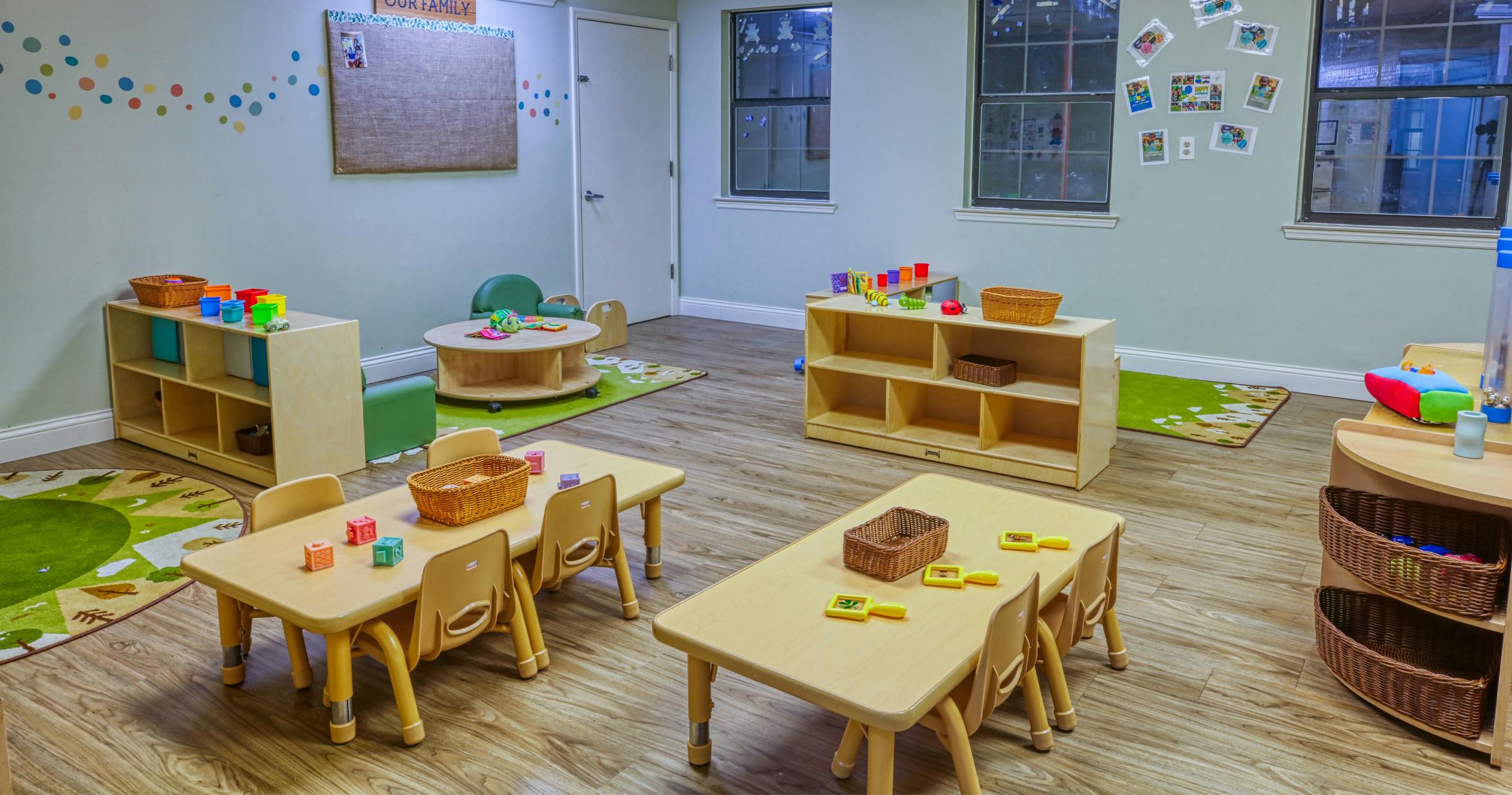 Classroom with small tables, chairs, shelving units, and toys