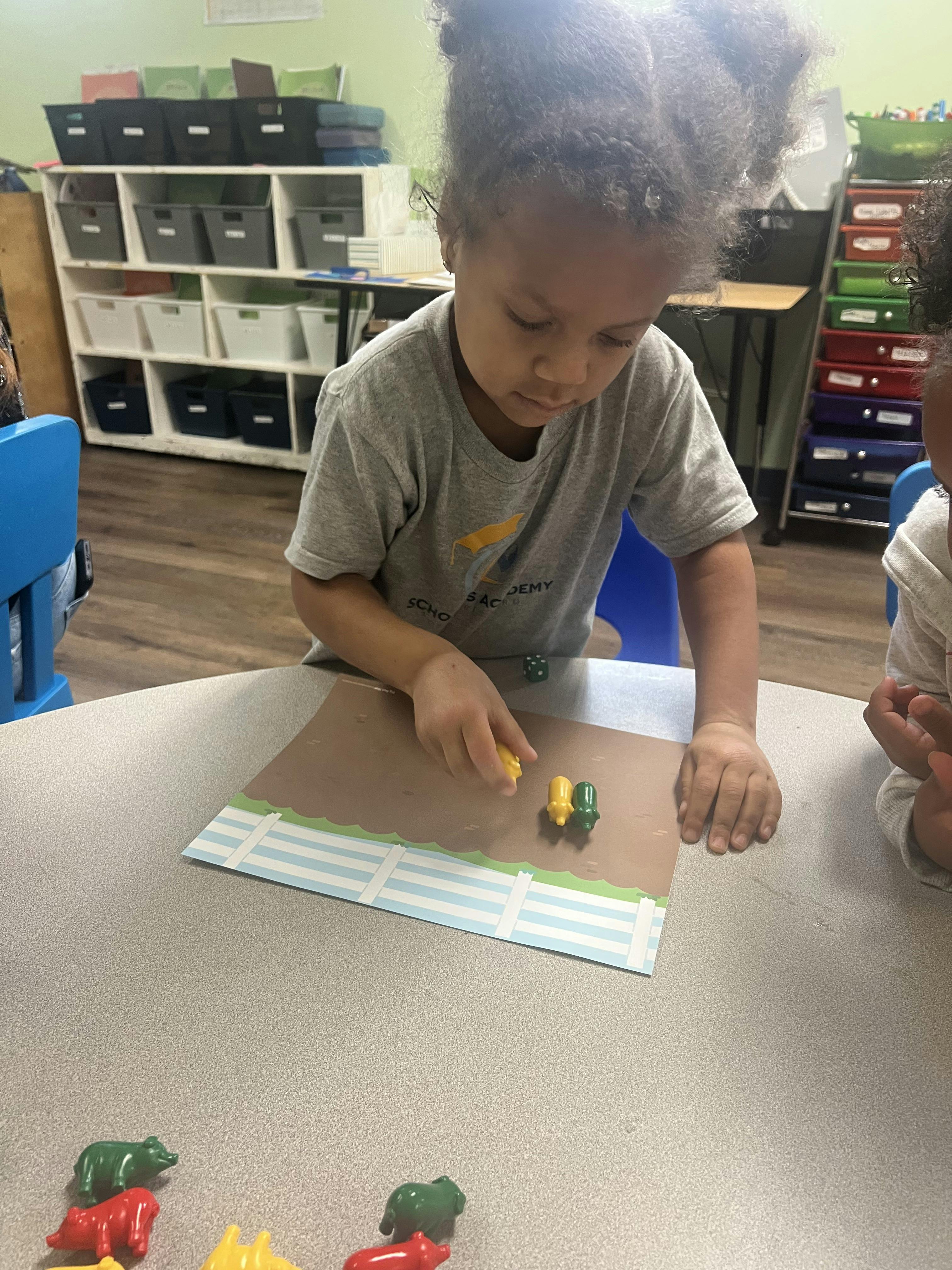 Child playing with animal figures and a die on a table