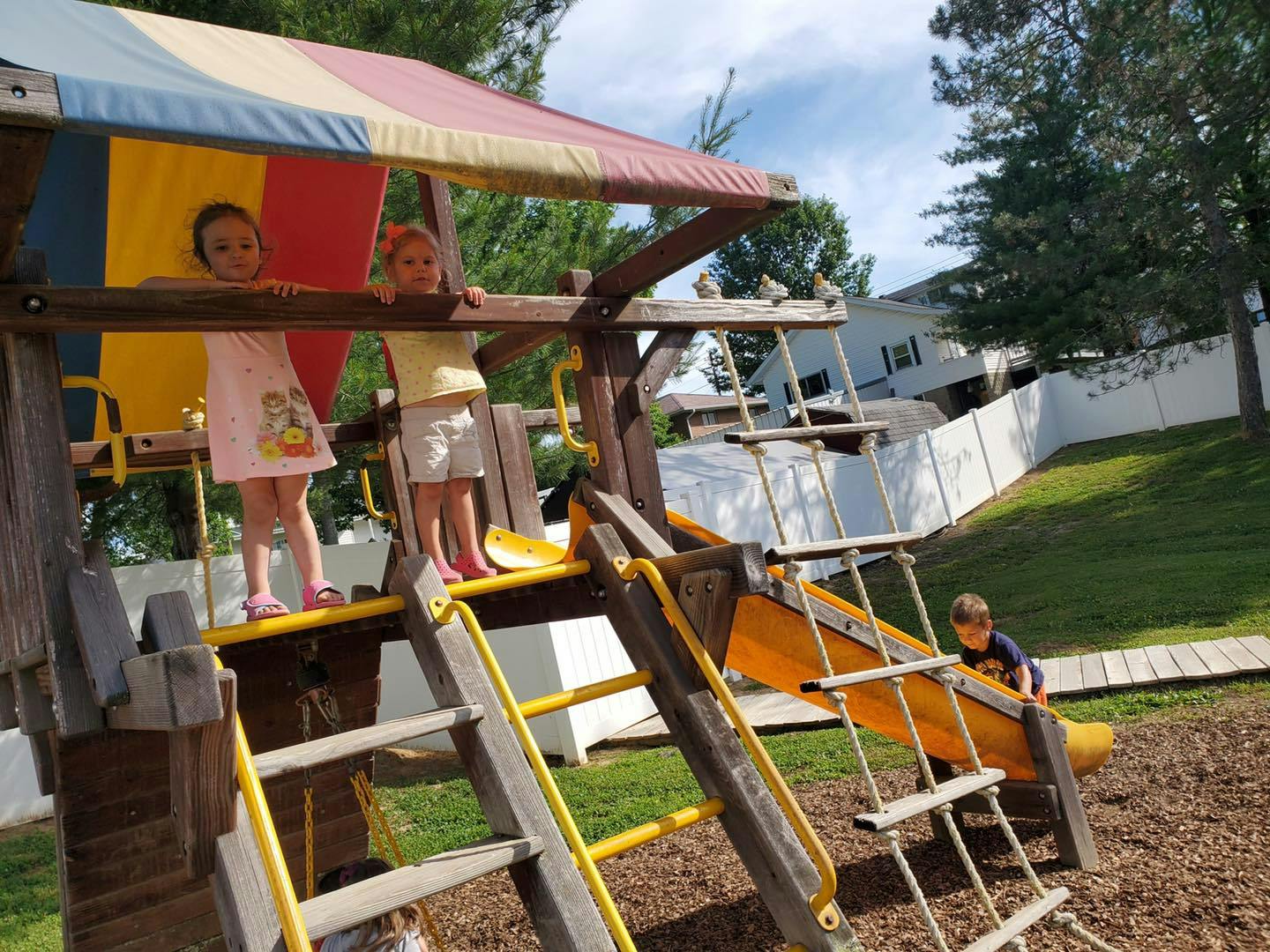 Children playing on a wooden playground structure with a slide