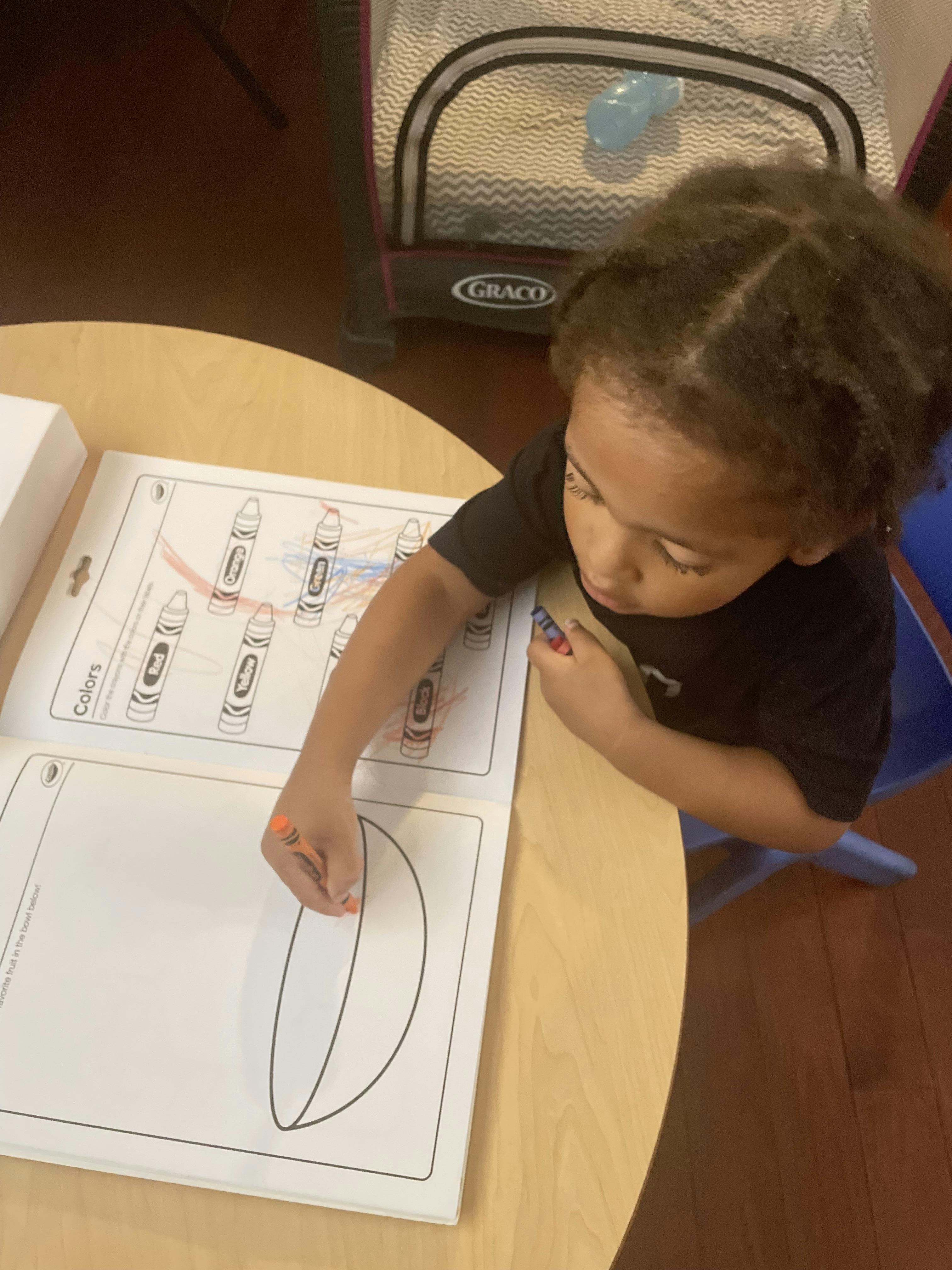 Child coloring in a book at a table