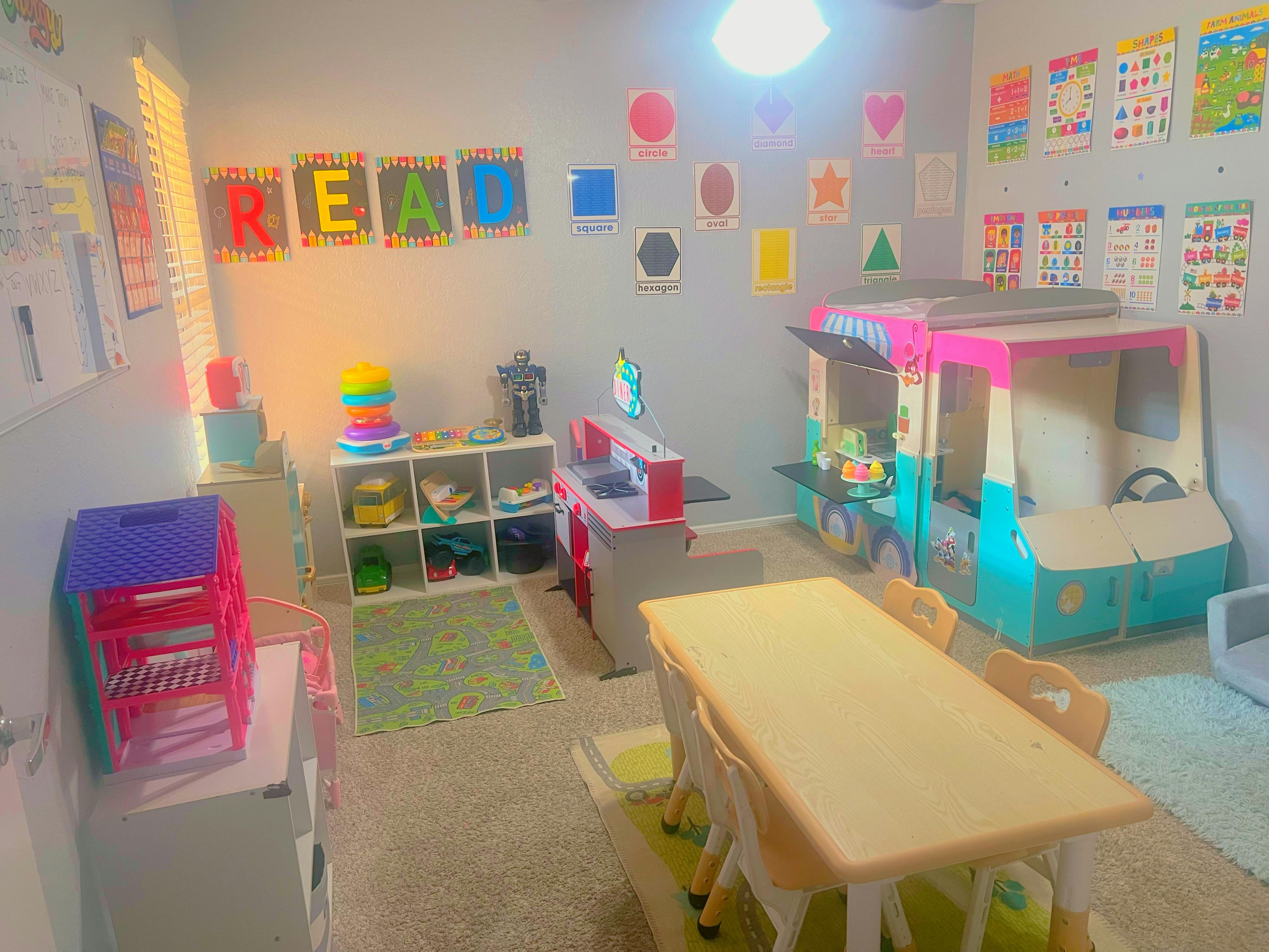 Playroom with a table and chairs, toy kitchen, and play car