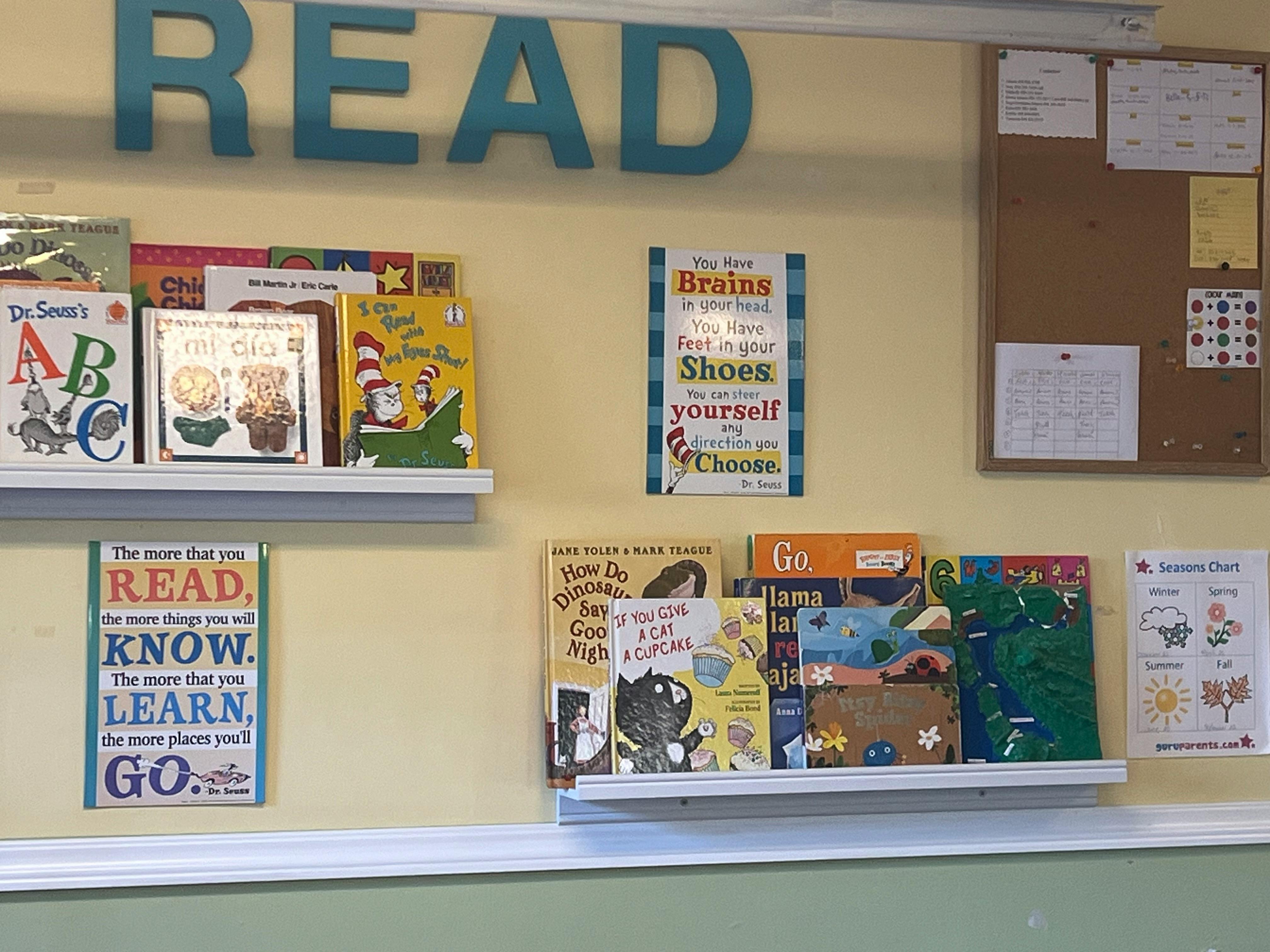 Wall with "READ" sign, two shelves of children's books, and posters