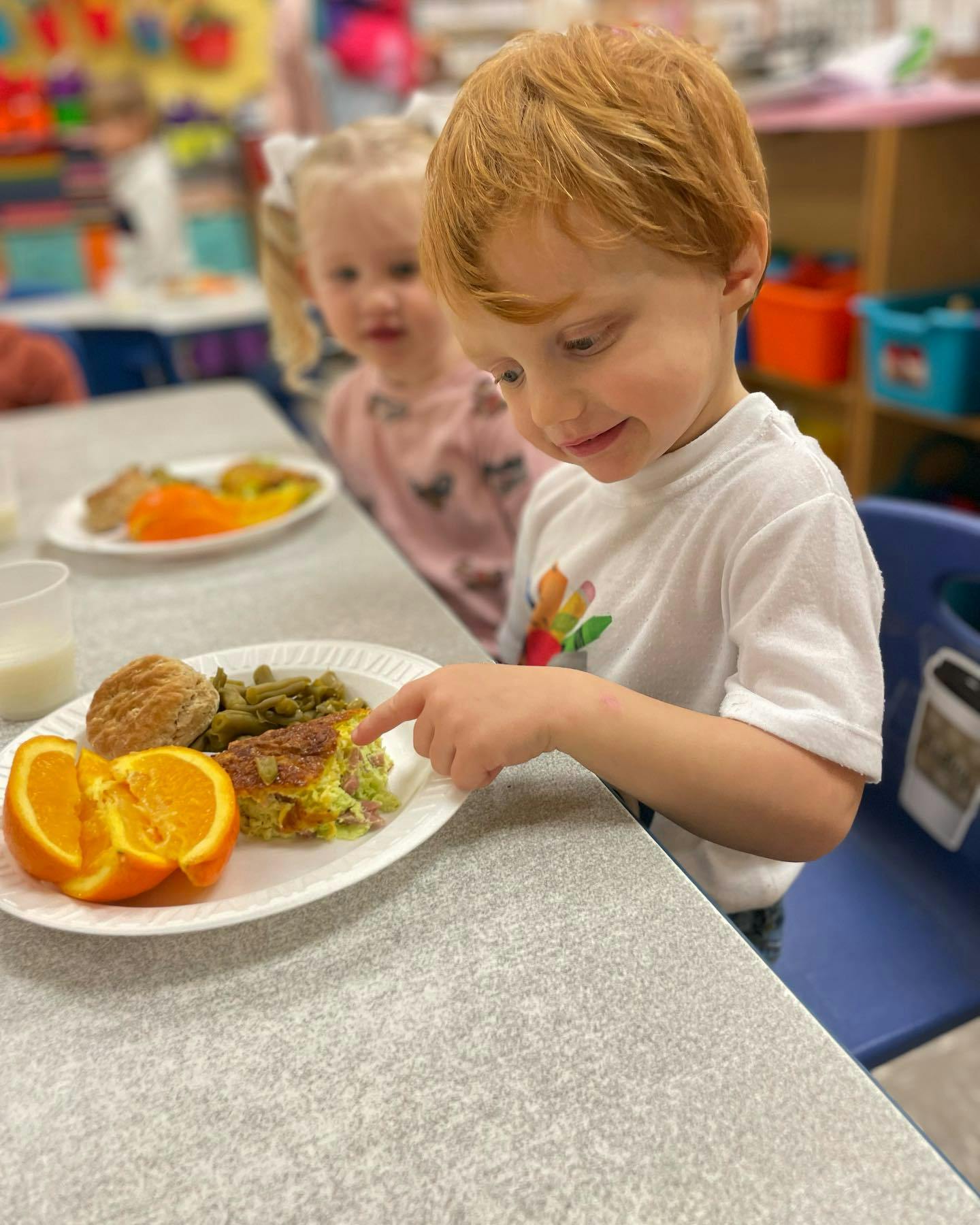 Child pointing at food on a plate at a table