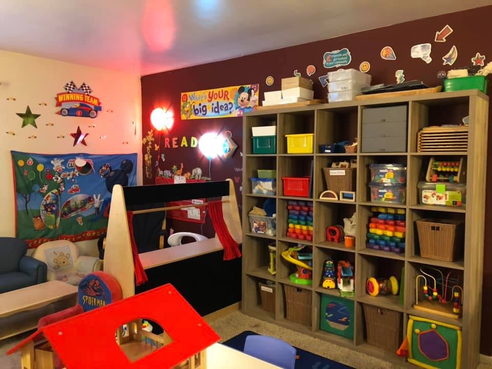 Playroom with a large shelving unit filled with toys and a small stage