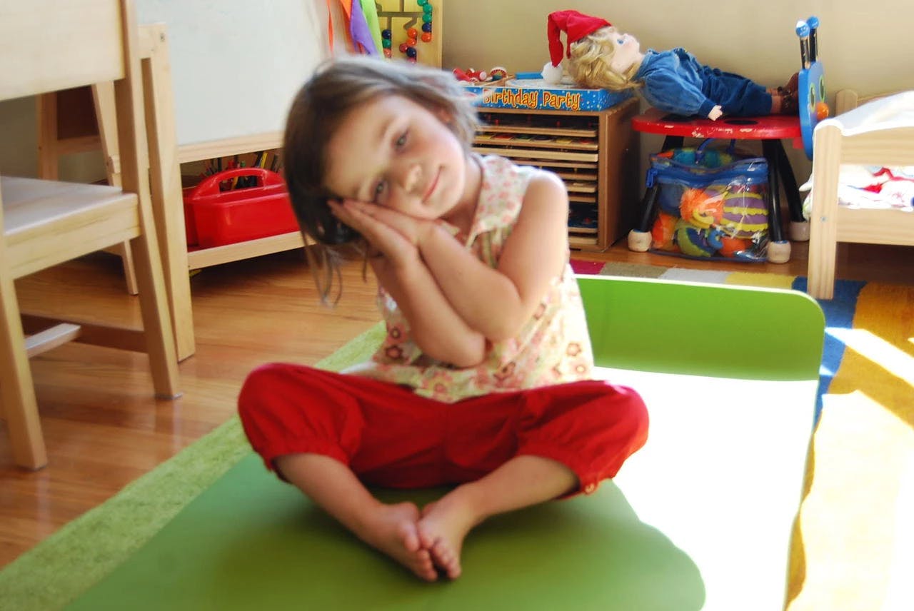 Child sitting with hands together under head, eyes closed