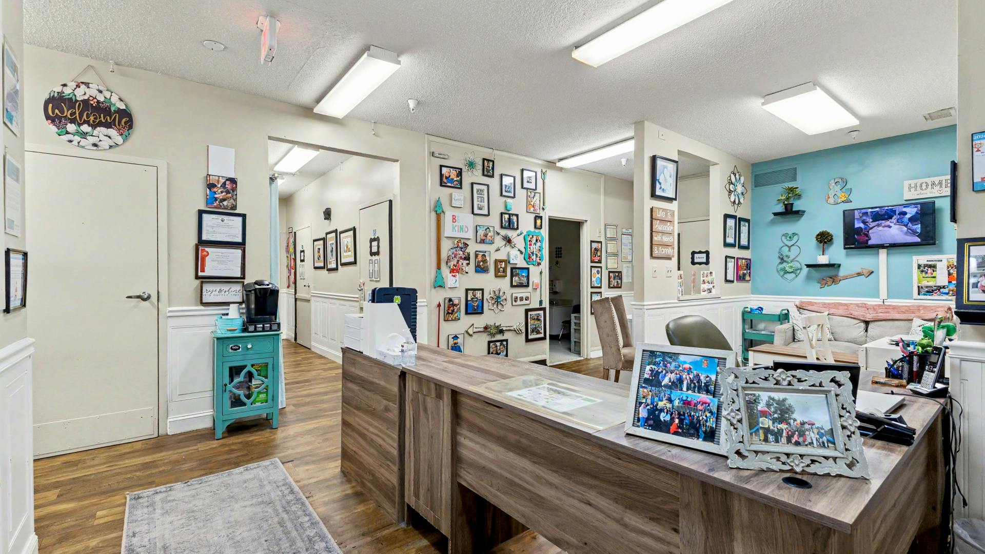 An office reception area with a wooden desk, decorated walls, and a waiting area