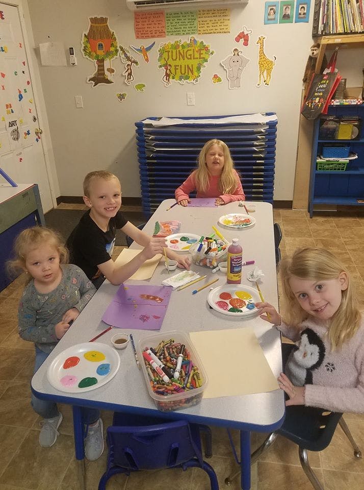 Four children painting and drawing at a table