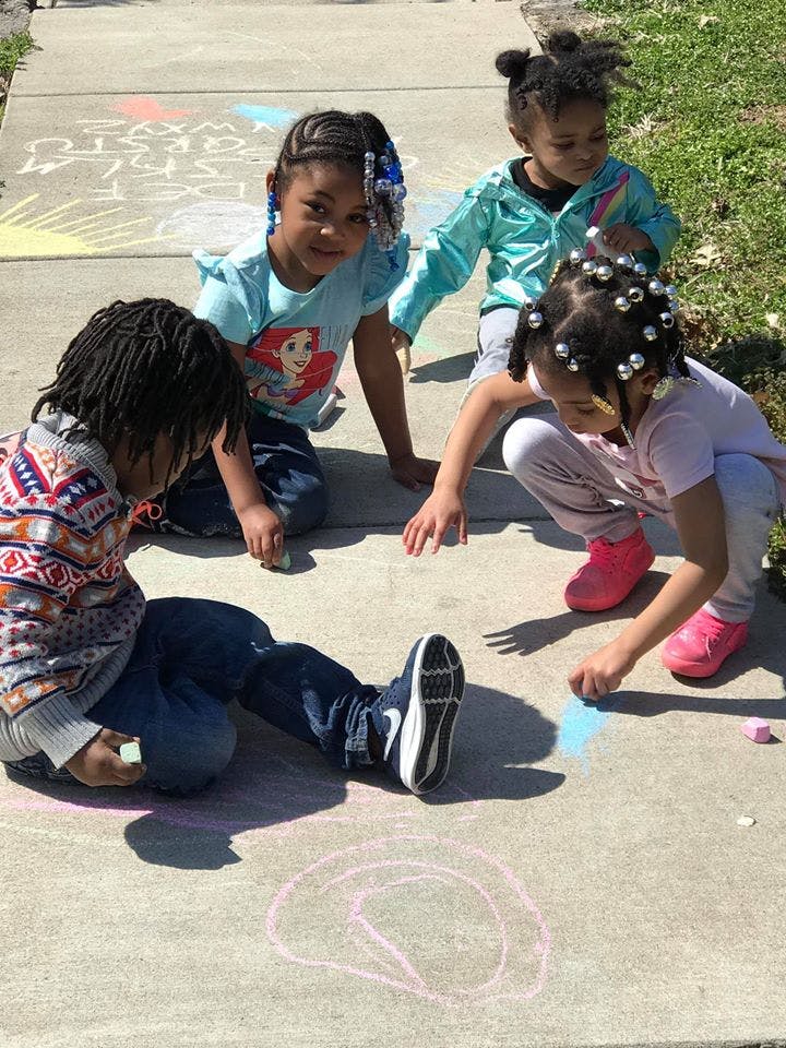 Four children drawing with chalk on a sidewalk