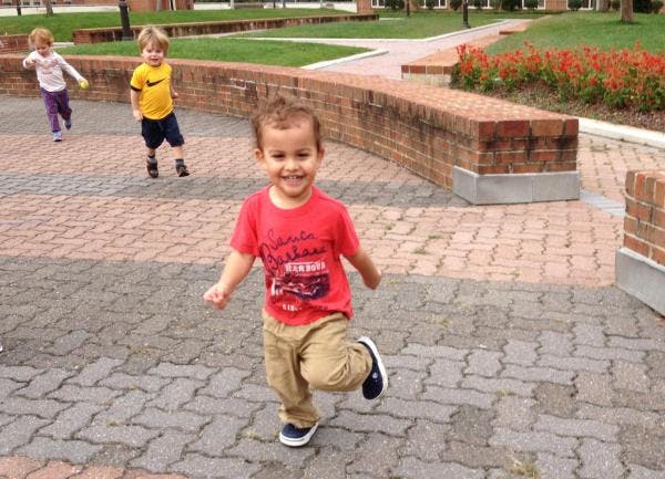 Three children running on a paved path