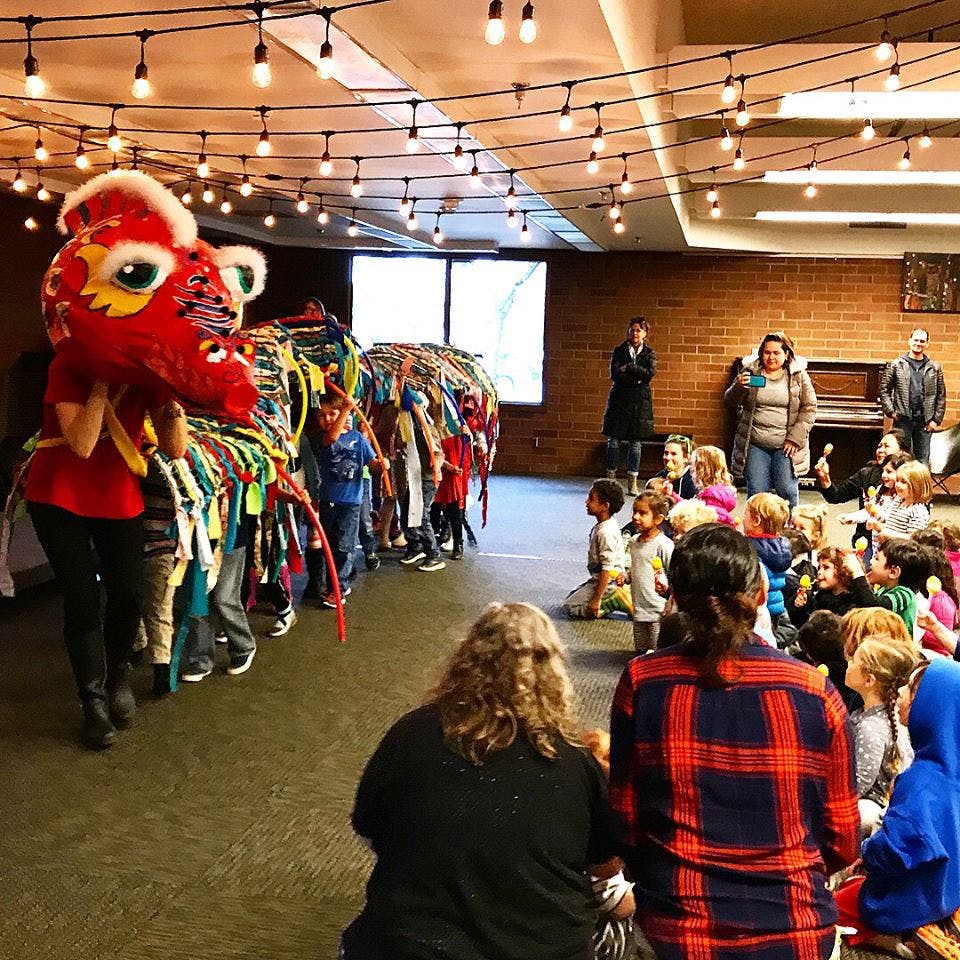 People and children watching a dragon costume performance