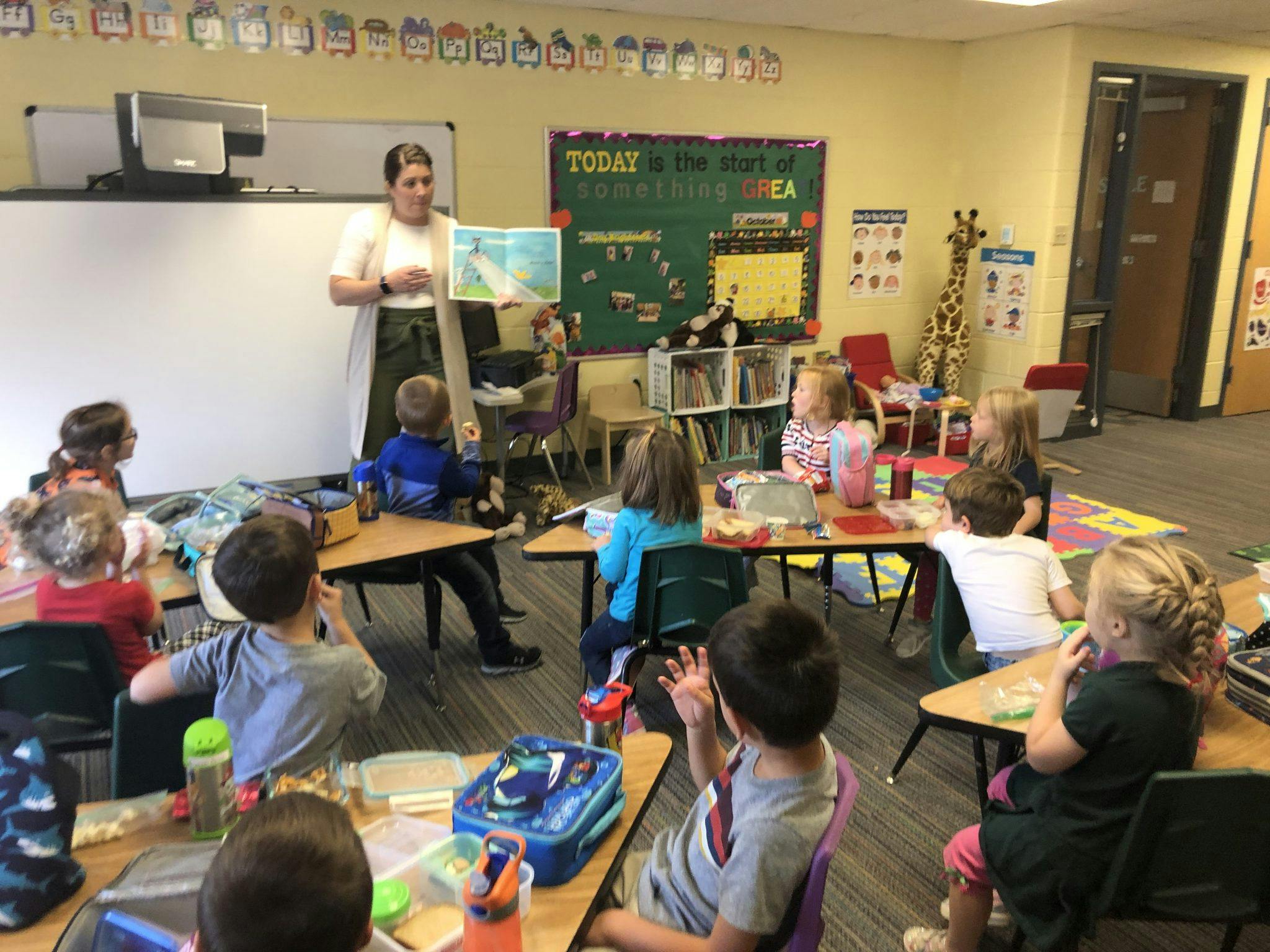 Adult reading a book to children in a classroom