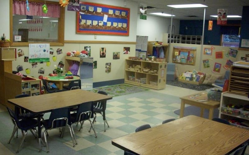 Classroom with child-sized tables and chairs, play areas, and educational displays