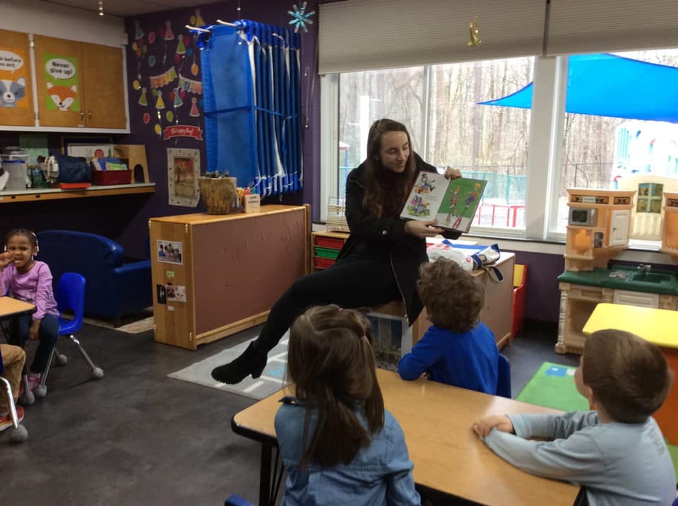 Person reading a book to children in a classroom
