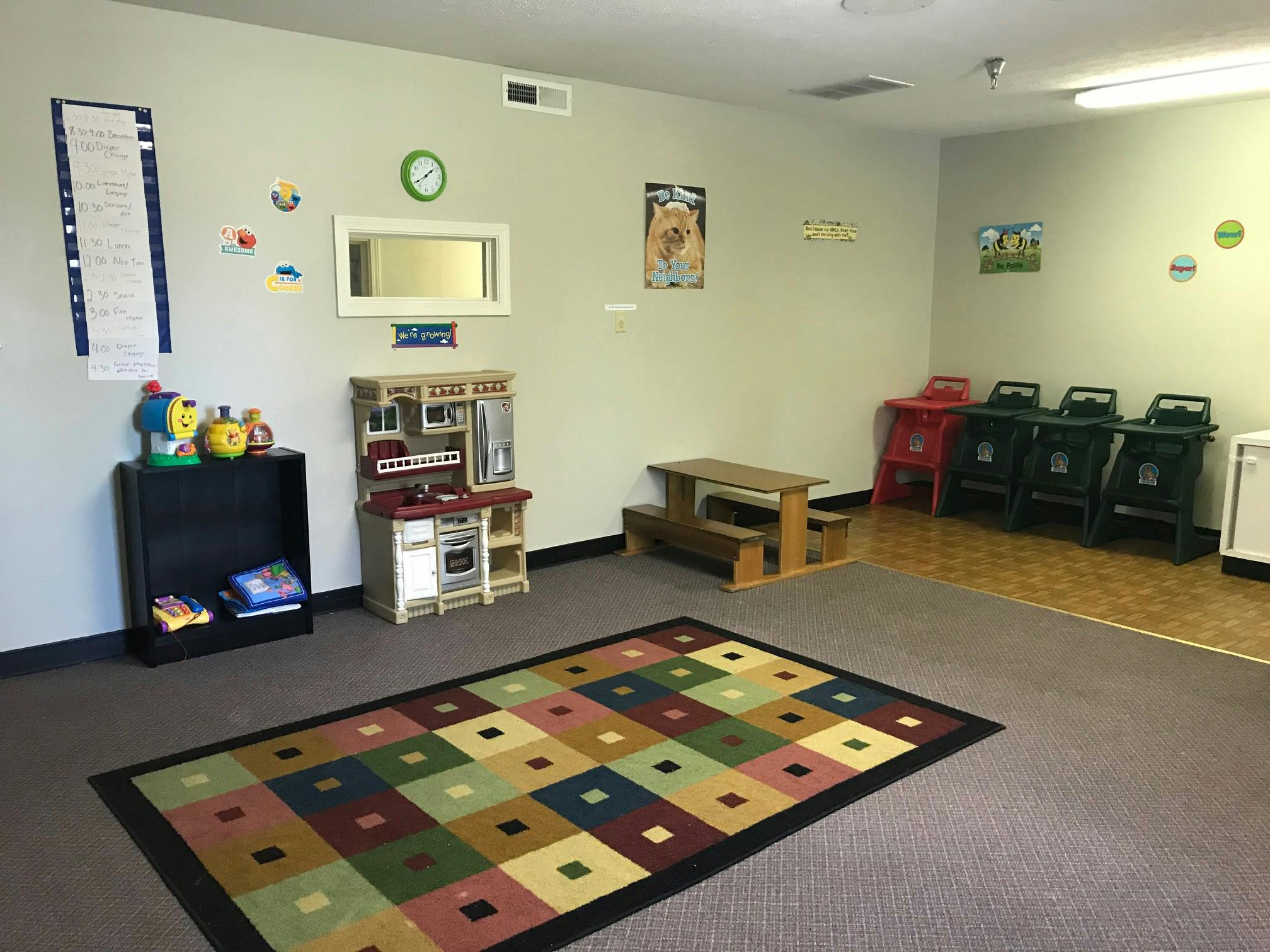 Playroom with a colorful rug, toy kitchen, and small picnic table