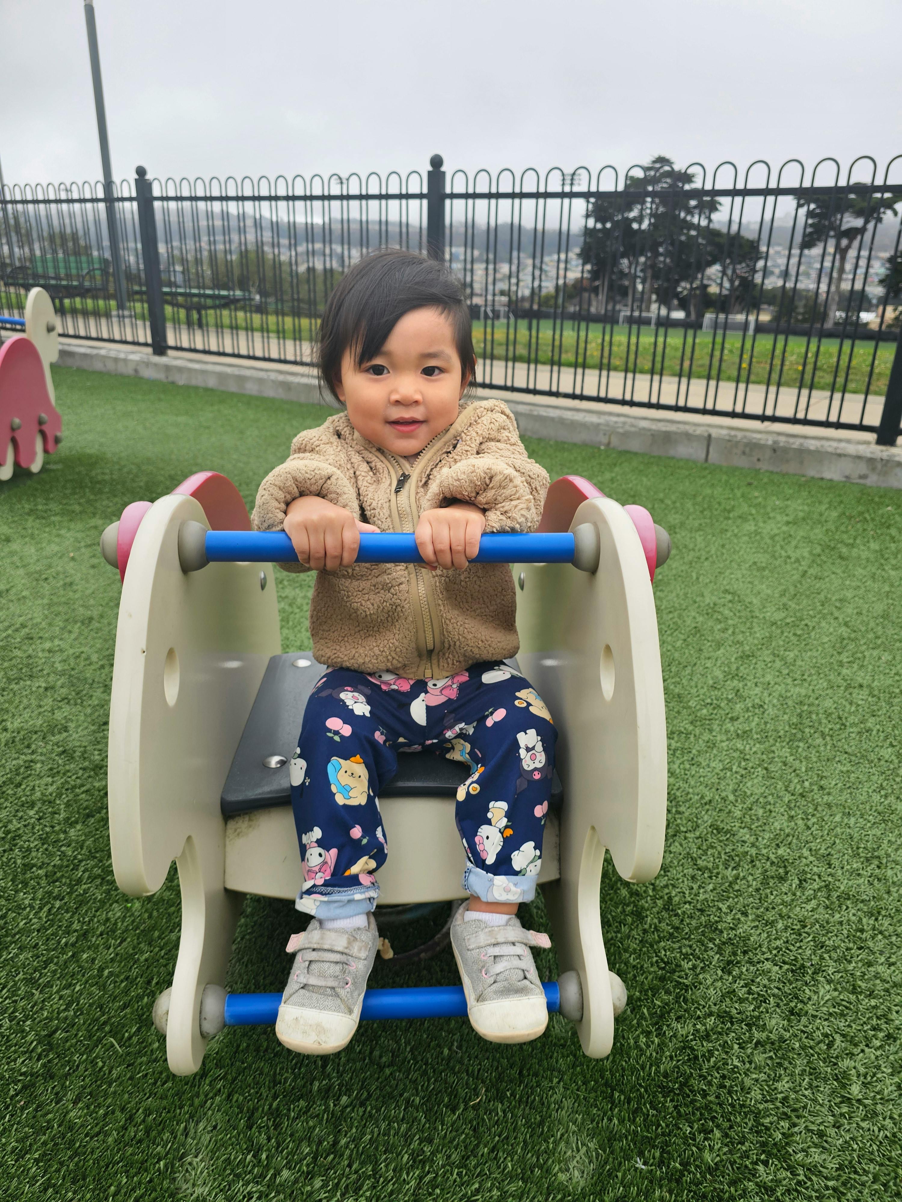 Child sitting on a small ride-on toy at a playground