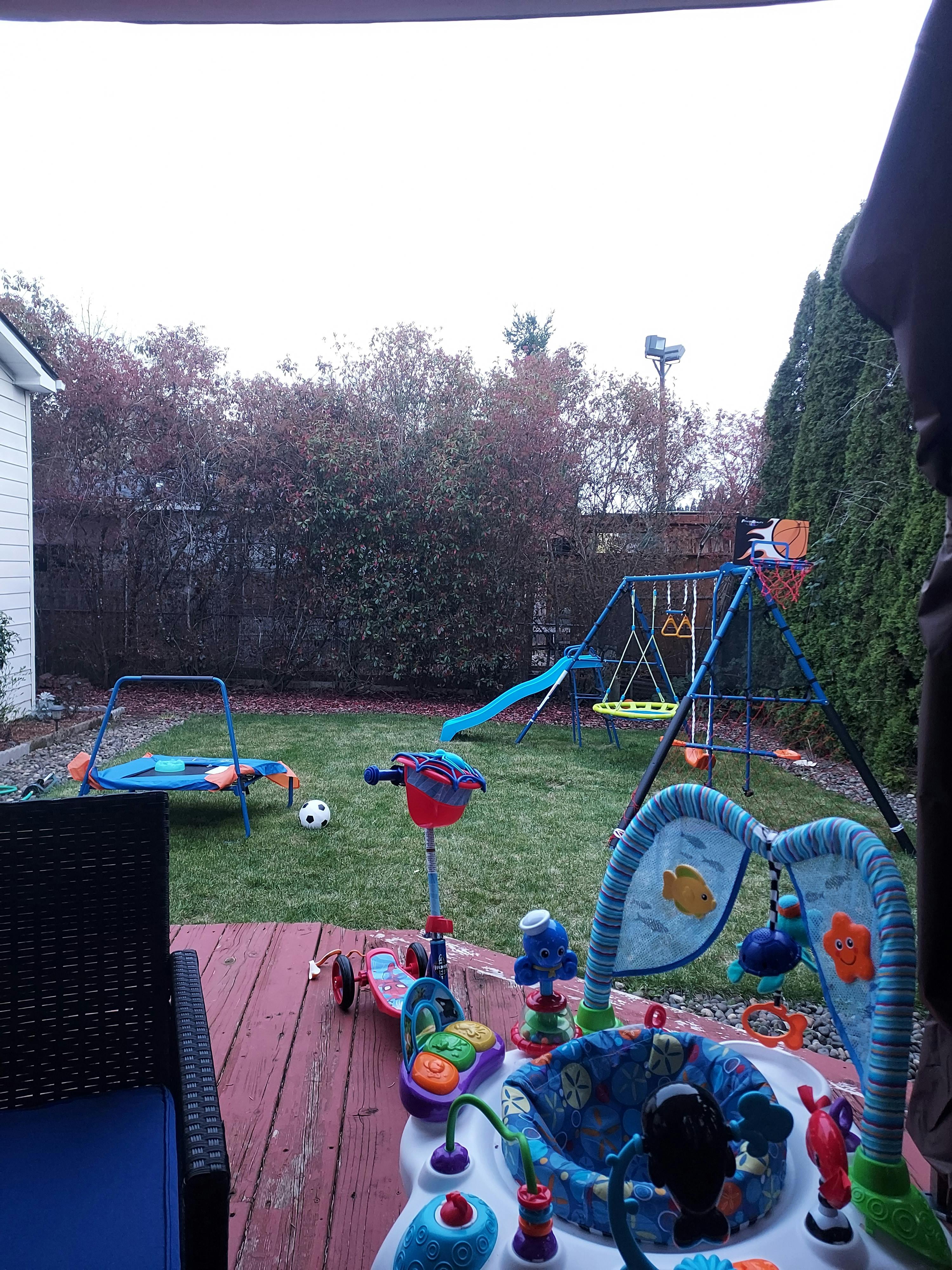 Backyard with a swing set, trampoline, and various children's toys