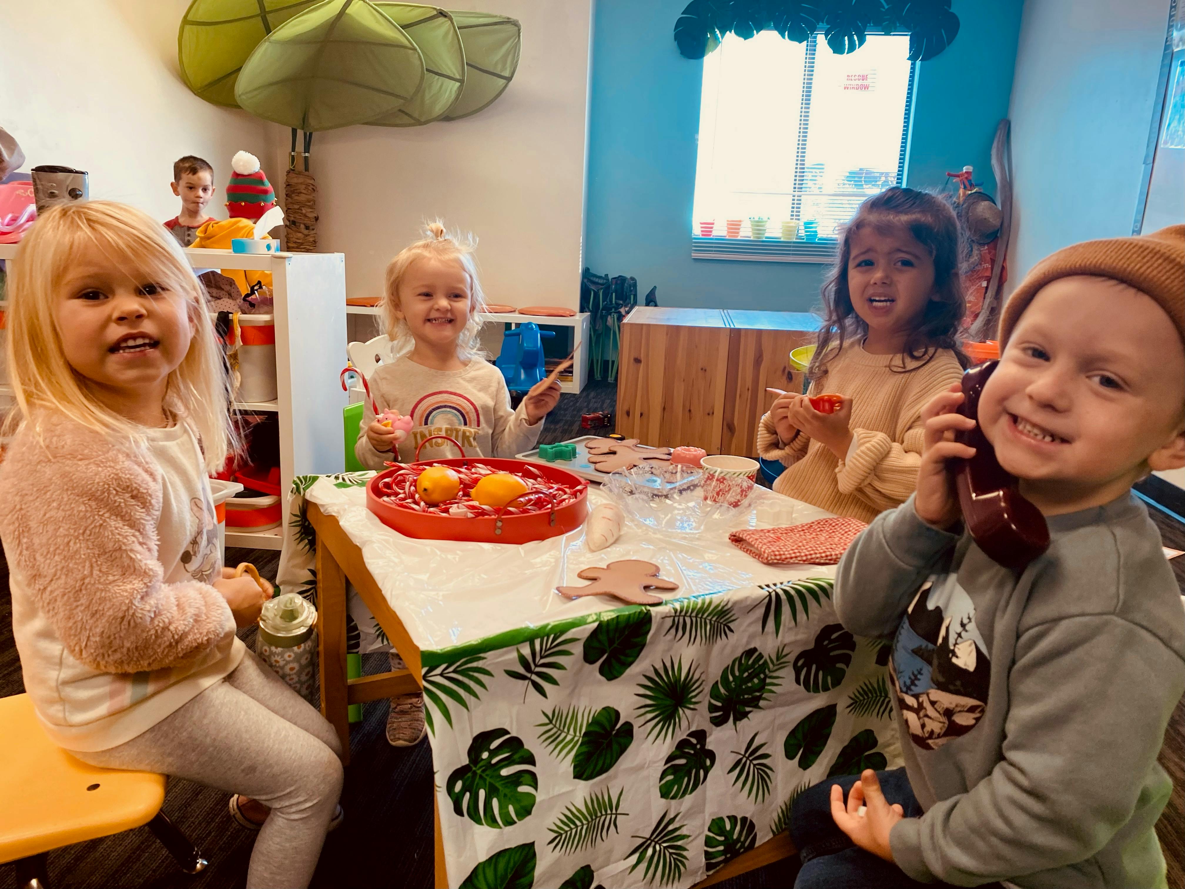 Four children sitting around a table with toys