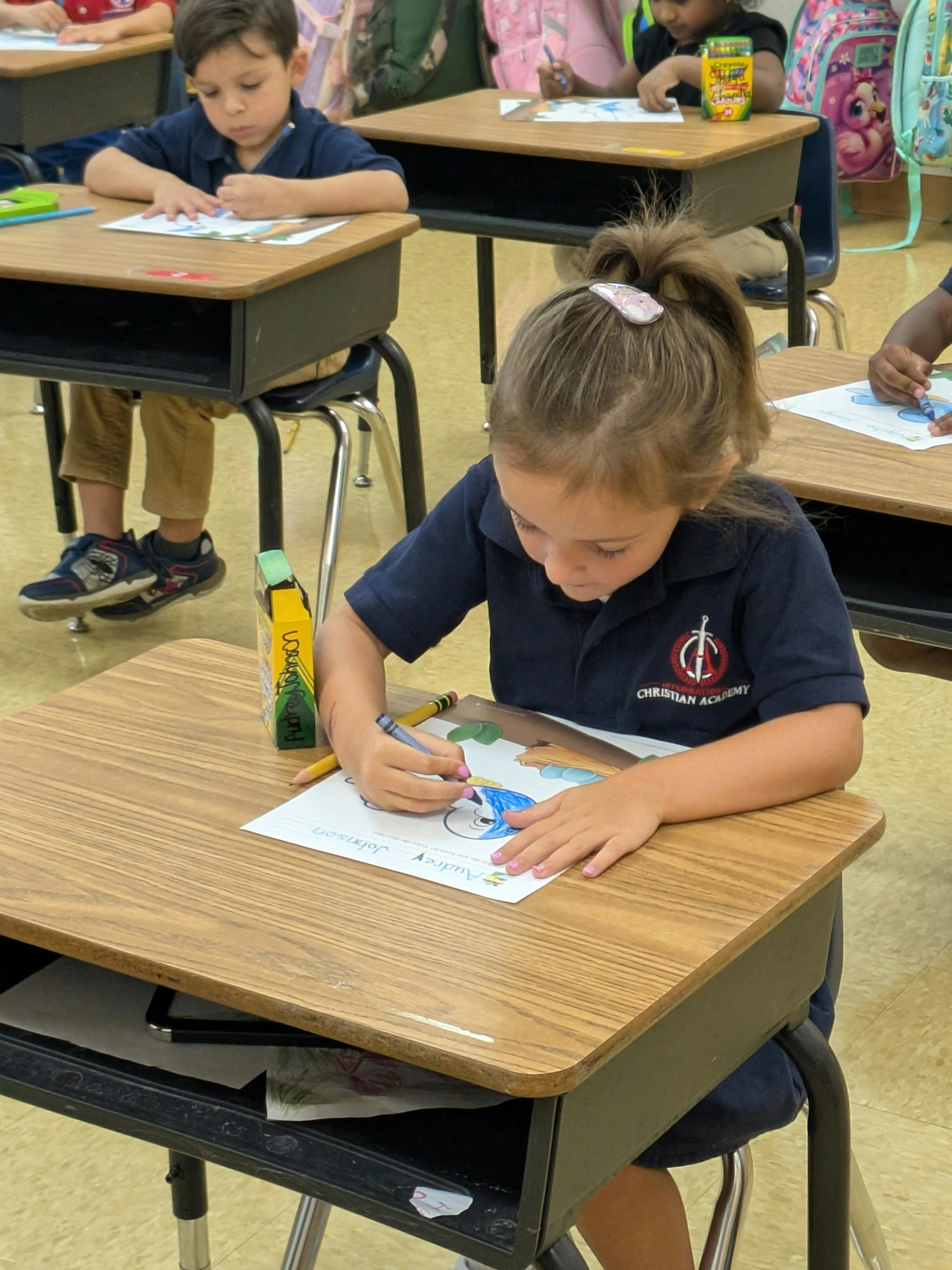 Child coloring at a desk in a classroom