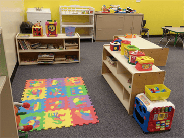 Playroom with colorful floor mat and shelves of toys