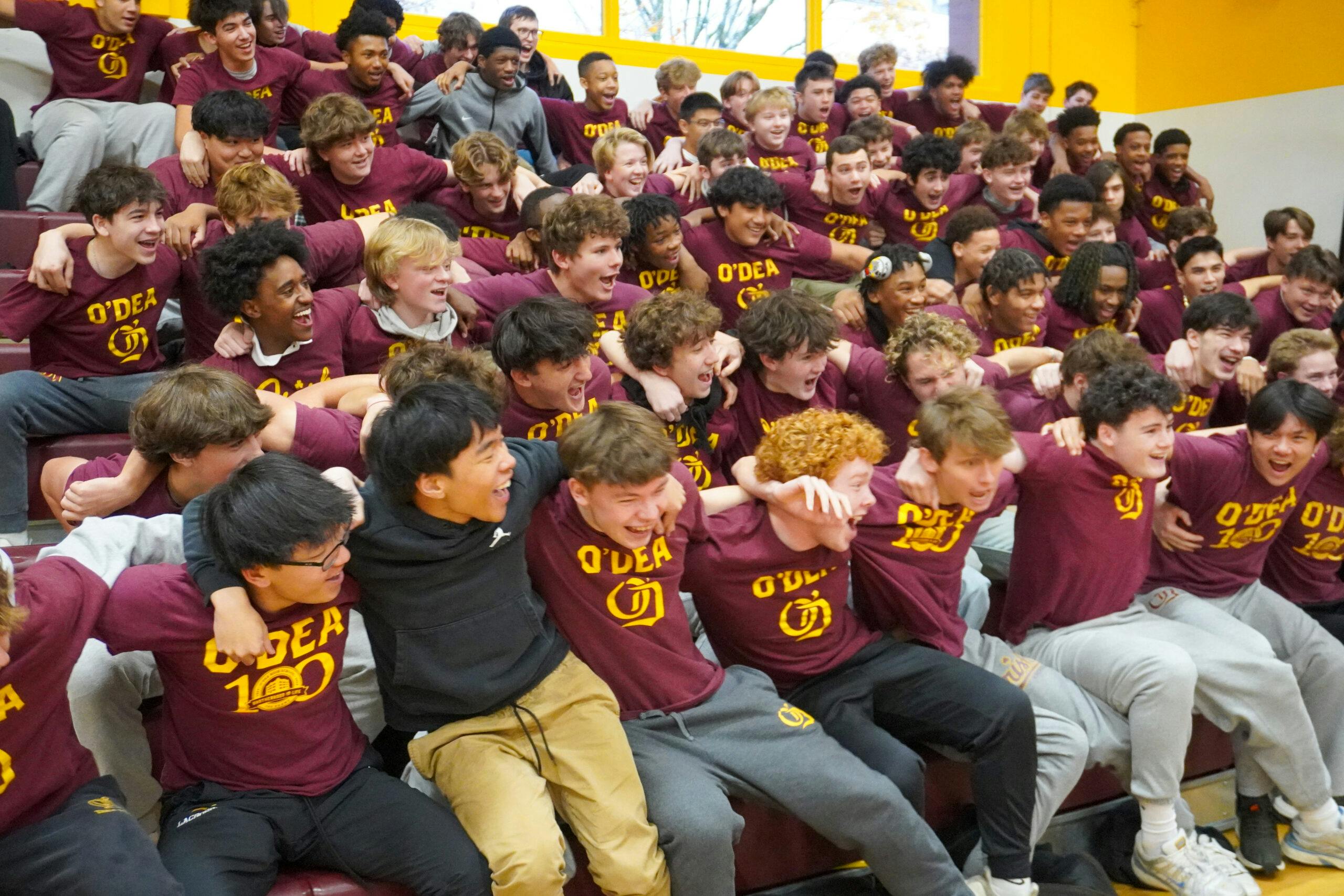 Group of laughing teens wearing O'Dea t-shirts and sitting in bleachers