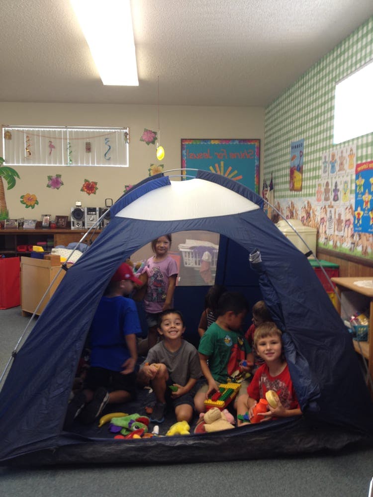Children playing inside a small tent in a classroom