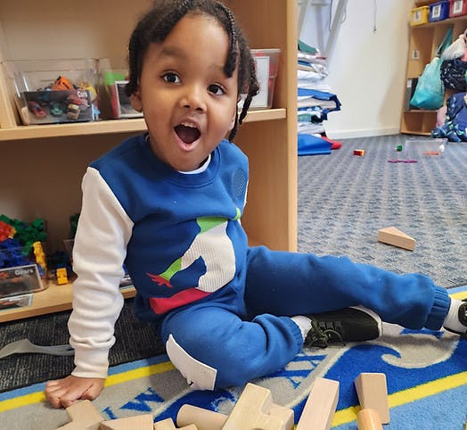 Child playing with wooden blocks on a rug