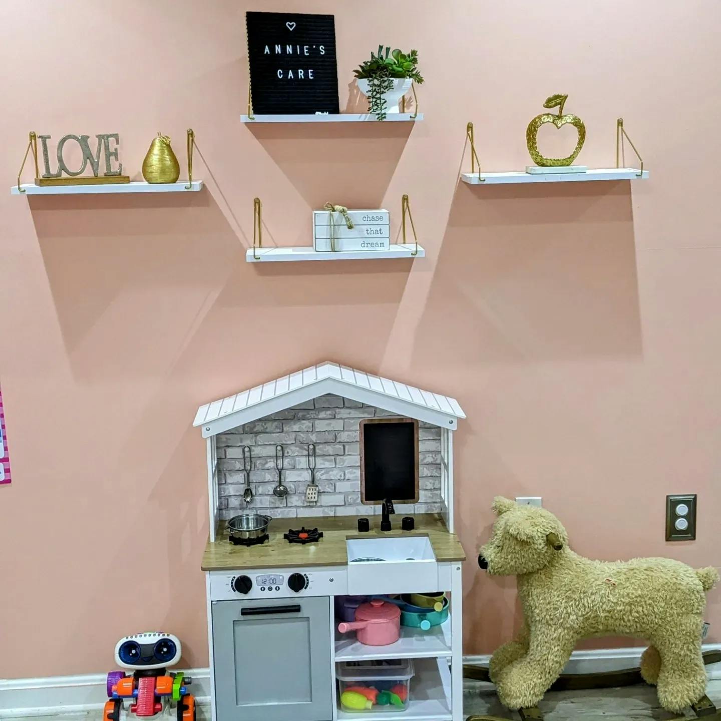 Play kitchen with shelves above and a stuffed dog next to it