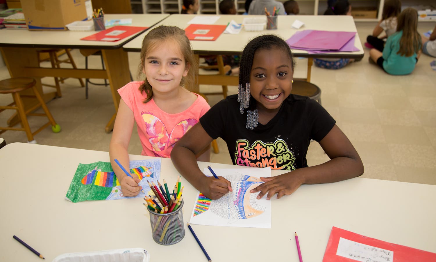 Two children drawing at a table in a classroom