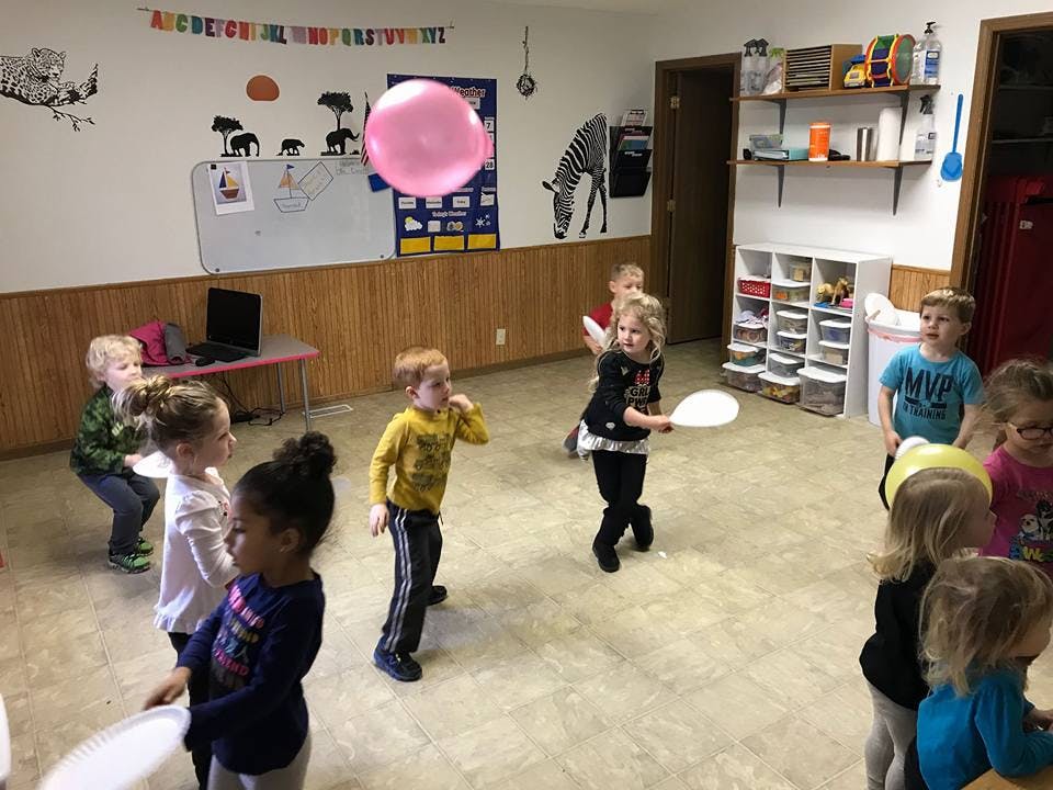 Children playing with a large pink balloon in a room