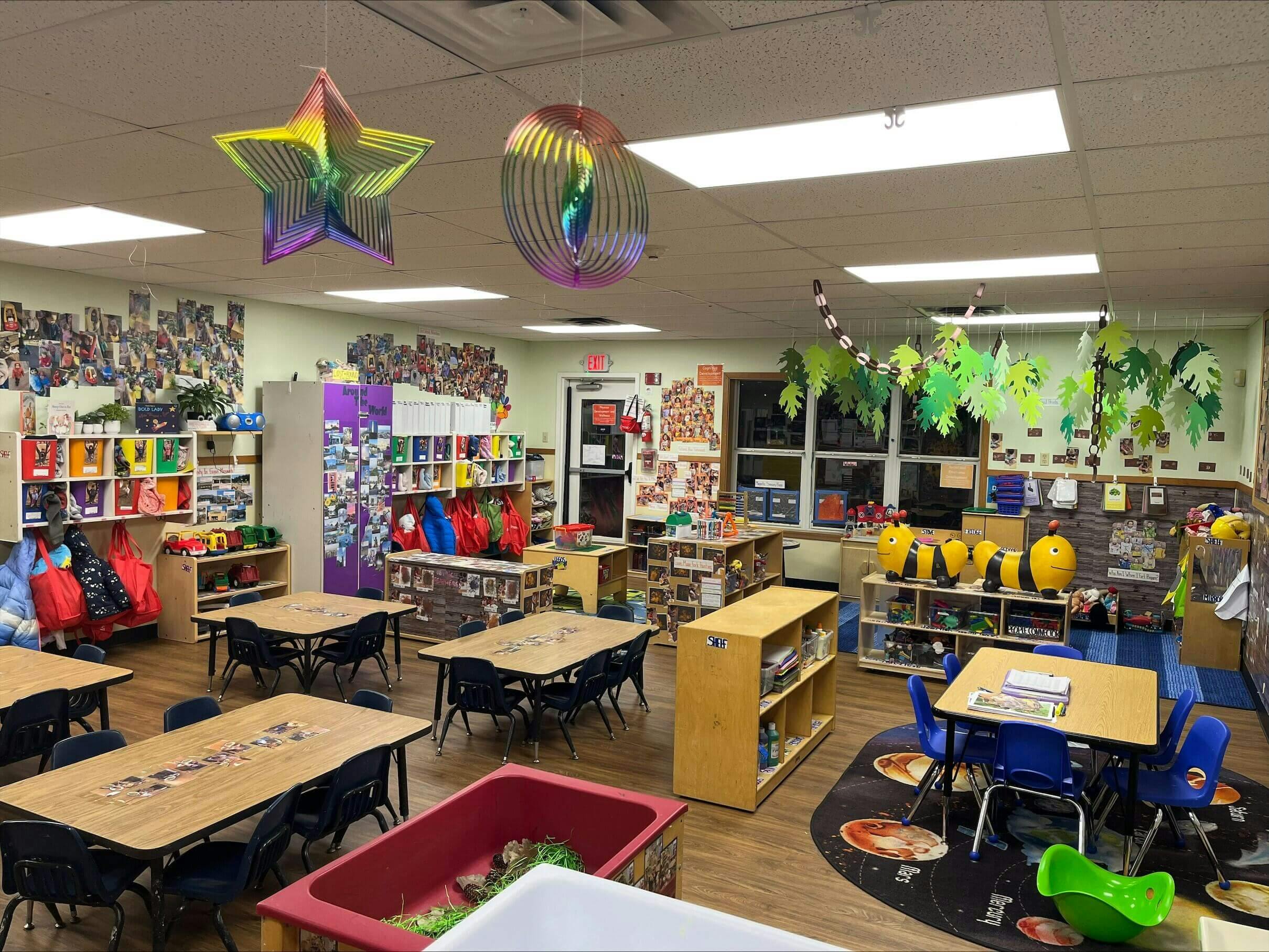 Colorful classroom with tables, chairs, shelving units, and decorations