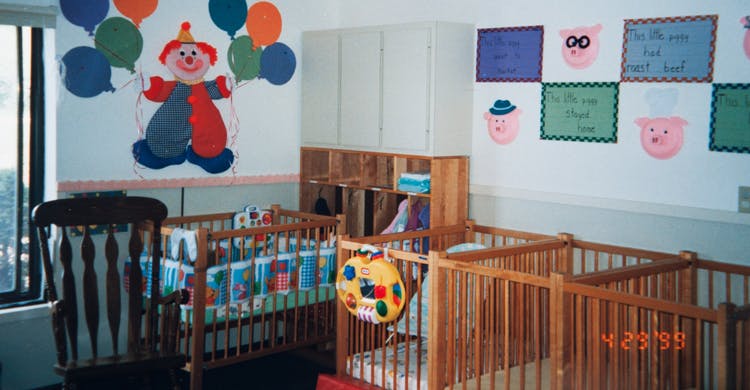 Nursery room with multiple wooden cribs and clown decoration on wall