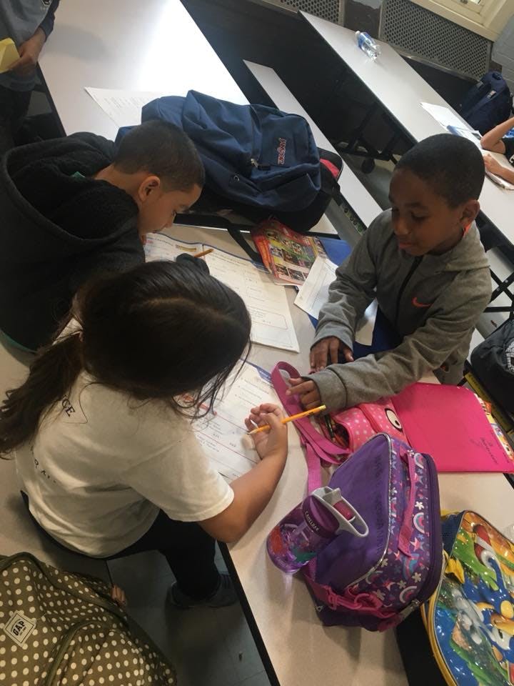 Three children drawing and writing at a table