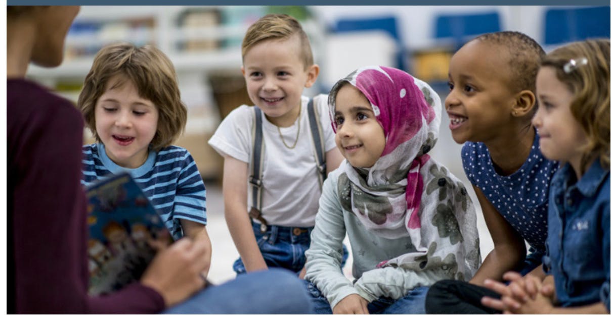 Adult reading a book to a group of children
