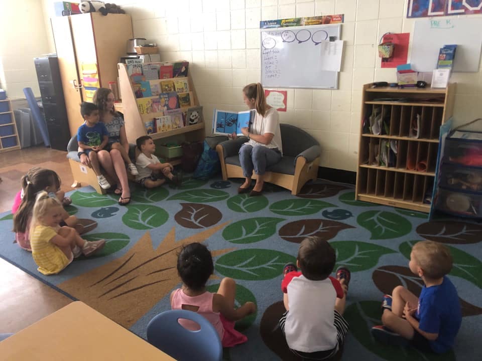 Adult reading a book to children in a classroom