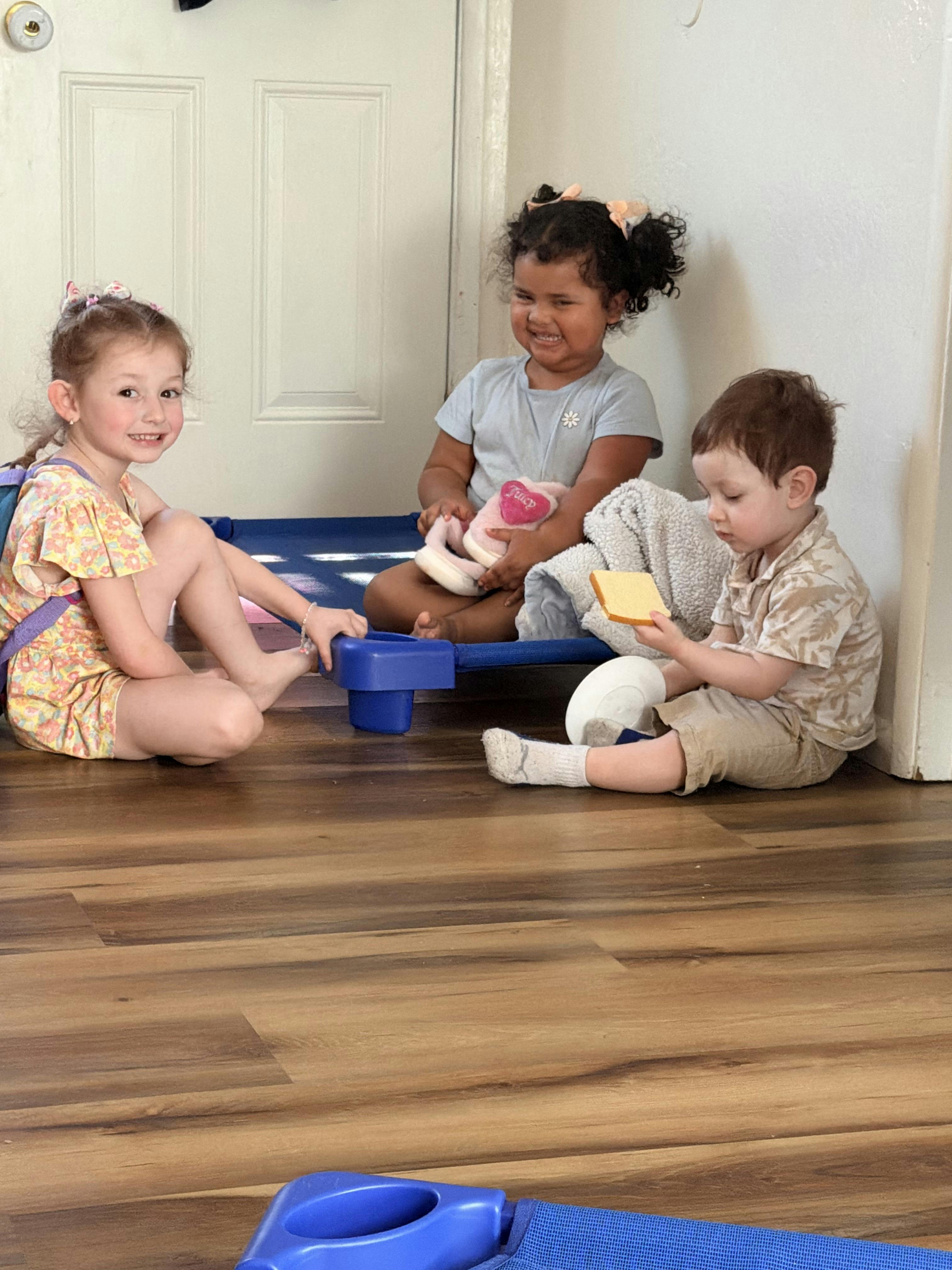 Three children playing on the floor, one holding a slice of bread